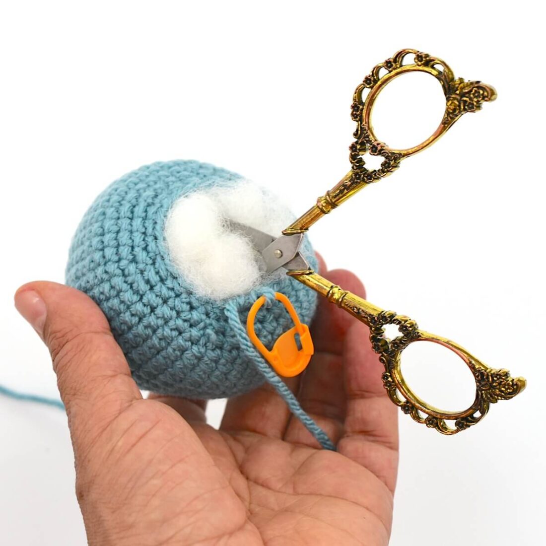 a hand holding yarn and scissors