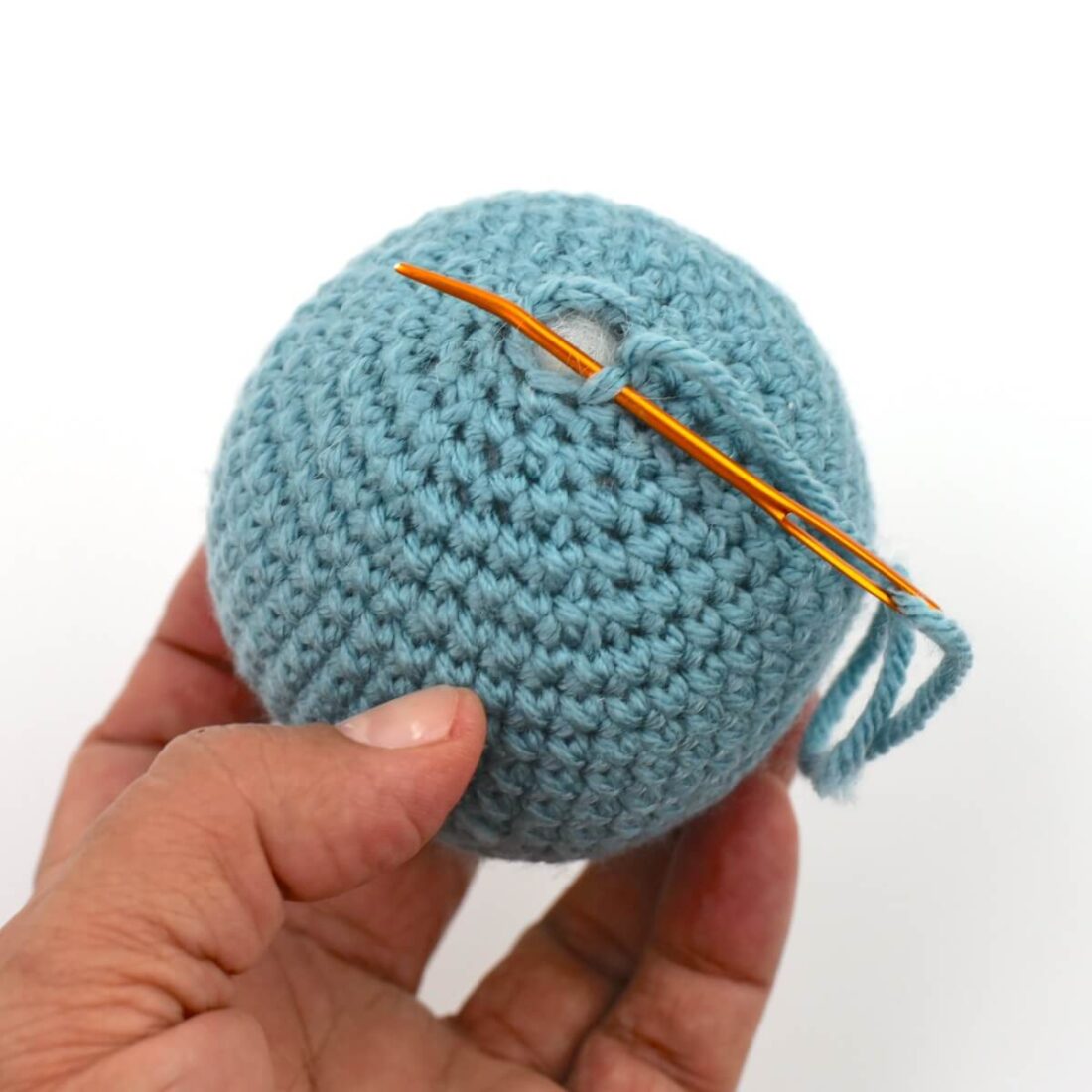 a hand holding yarn and needle