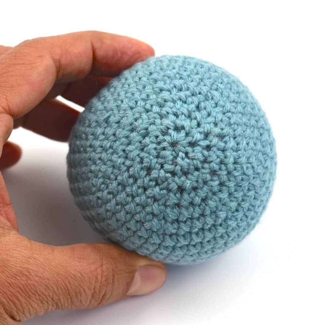 a hand holding a crochet ball