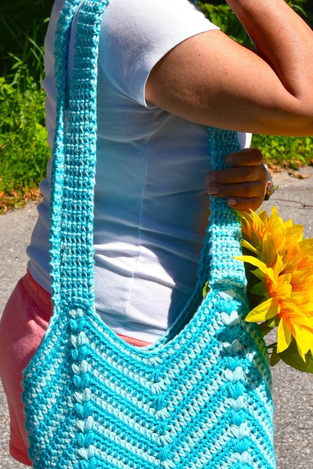 a womean wearing a blue crochet tote bag on her shoulders