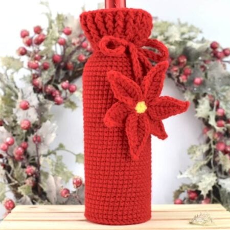 Front view of the crochet wine bottle cozy with textured ribbed stitches and holiday bottle inside.