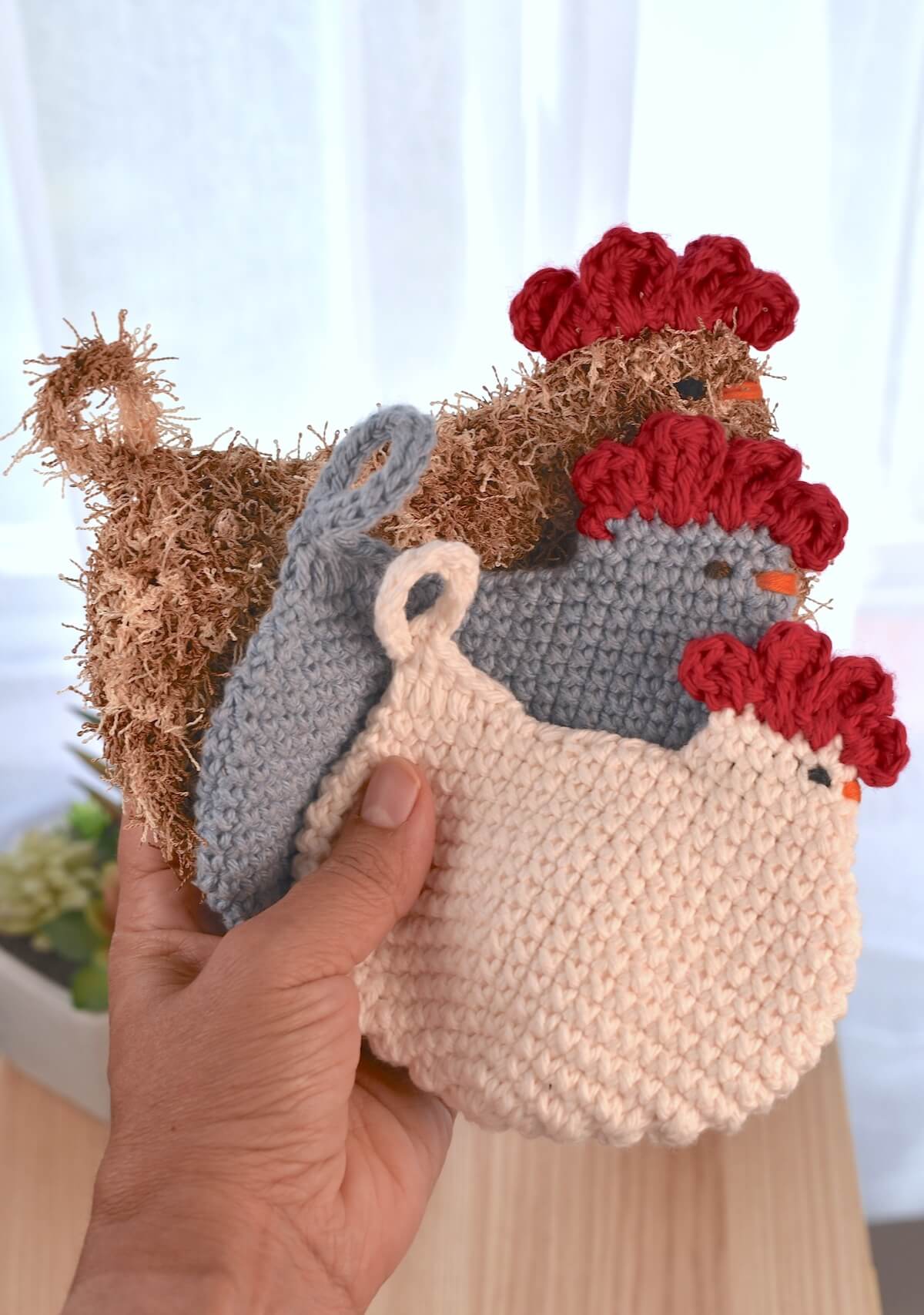 Set of chicken-shaped crochet dish scrubbies in different yarn textures and colors, perfect for cleaning pots and pans.