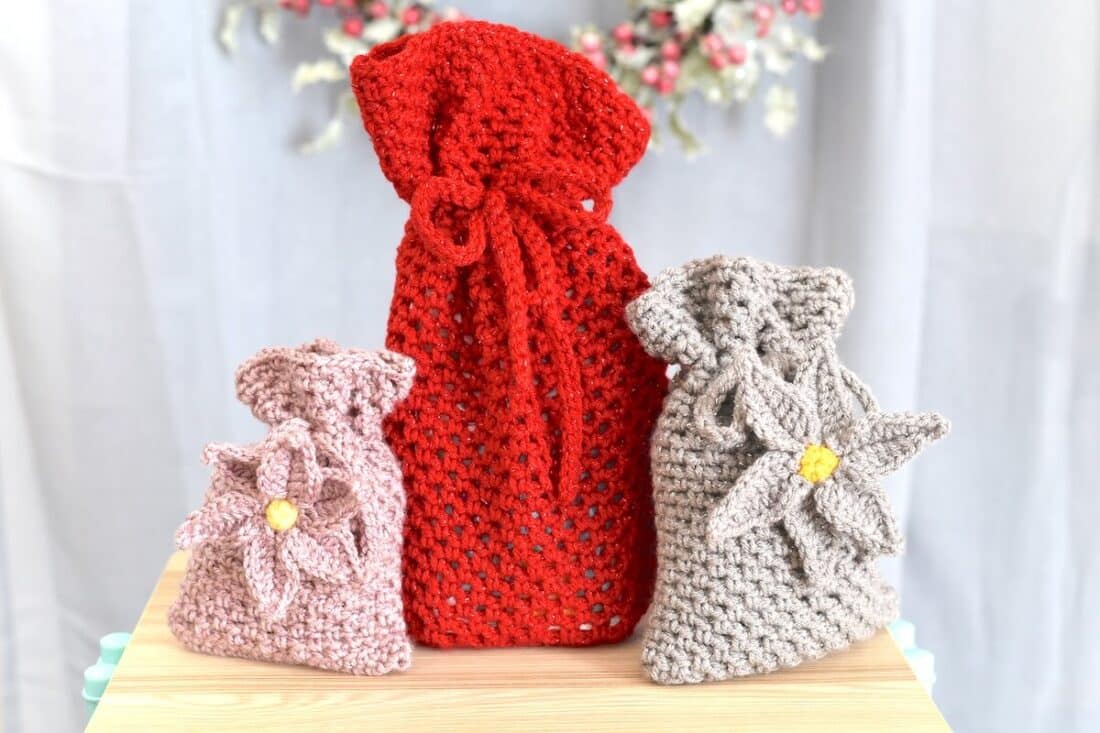 Handmade crochet drawstring bag pattern made with the mesh stitch in three different sizes.