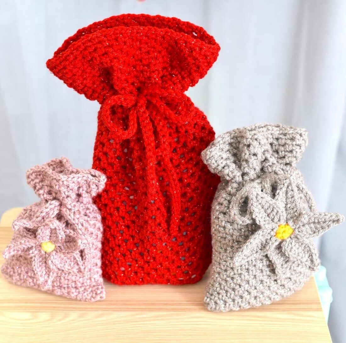Crochet gift bag pattern in three sizes with one red mesh bag and two textured smaller bags.
