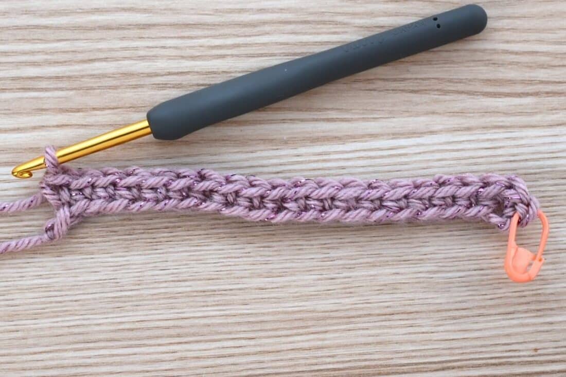 Detailed view of the crochet stitches on the first round using light mauve yarn with metallic thread.