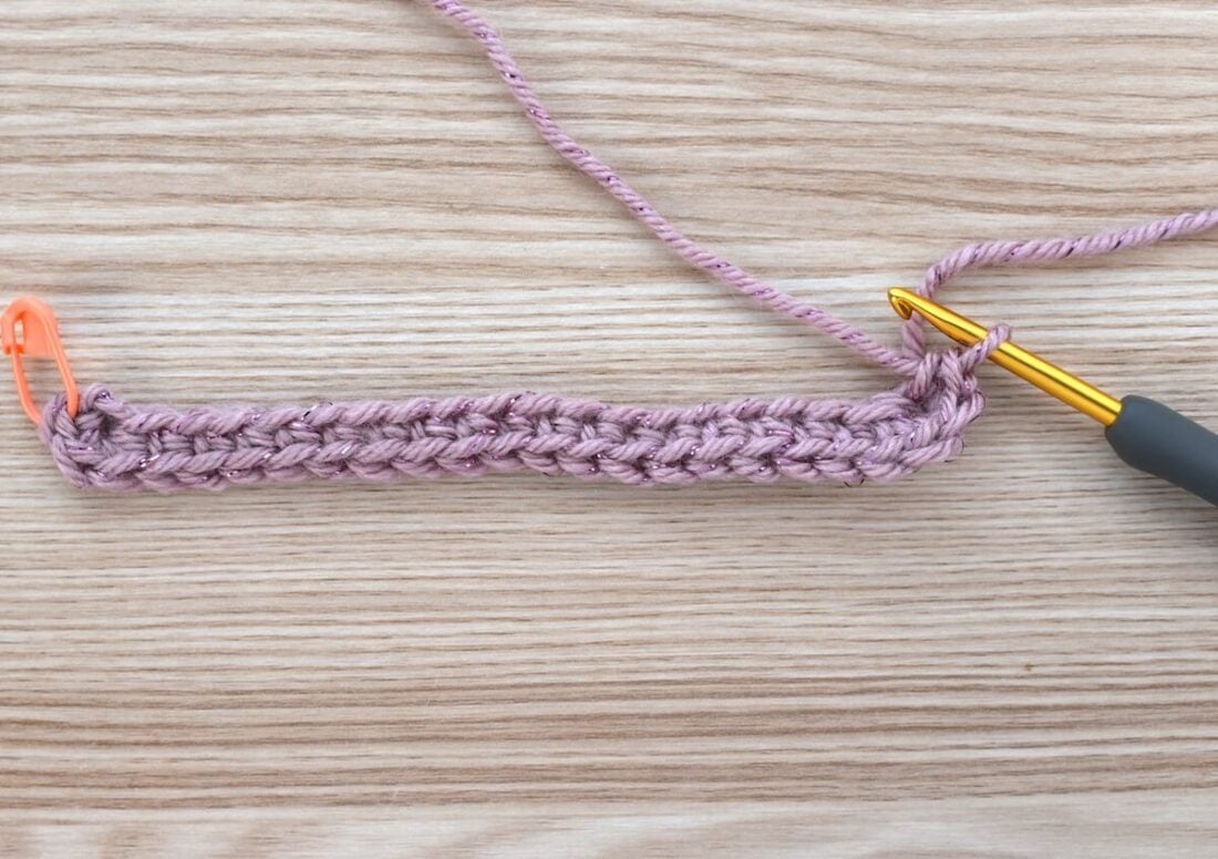 Close-up of the crochet bag base after completing the first half of the first round in single crochet.