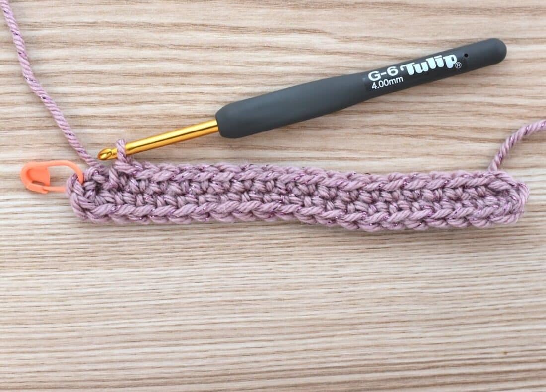 Close-up of the crochet bag base after completing the first round in single crochet.