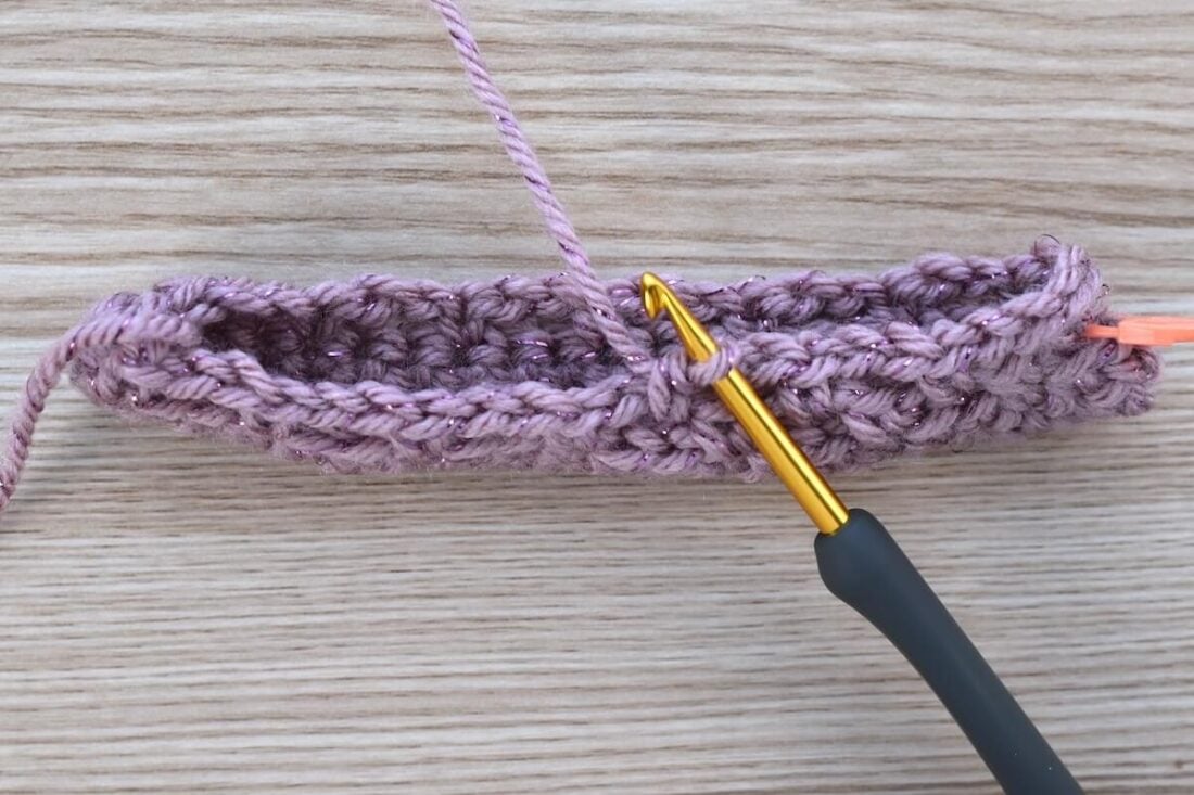Early stage of a crochet gift bag base lying flat on a wooden background.