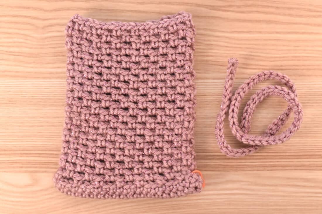 Close-up of the completed crochet bag after finishing the body of the bag, with the string laying on its side.