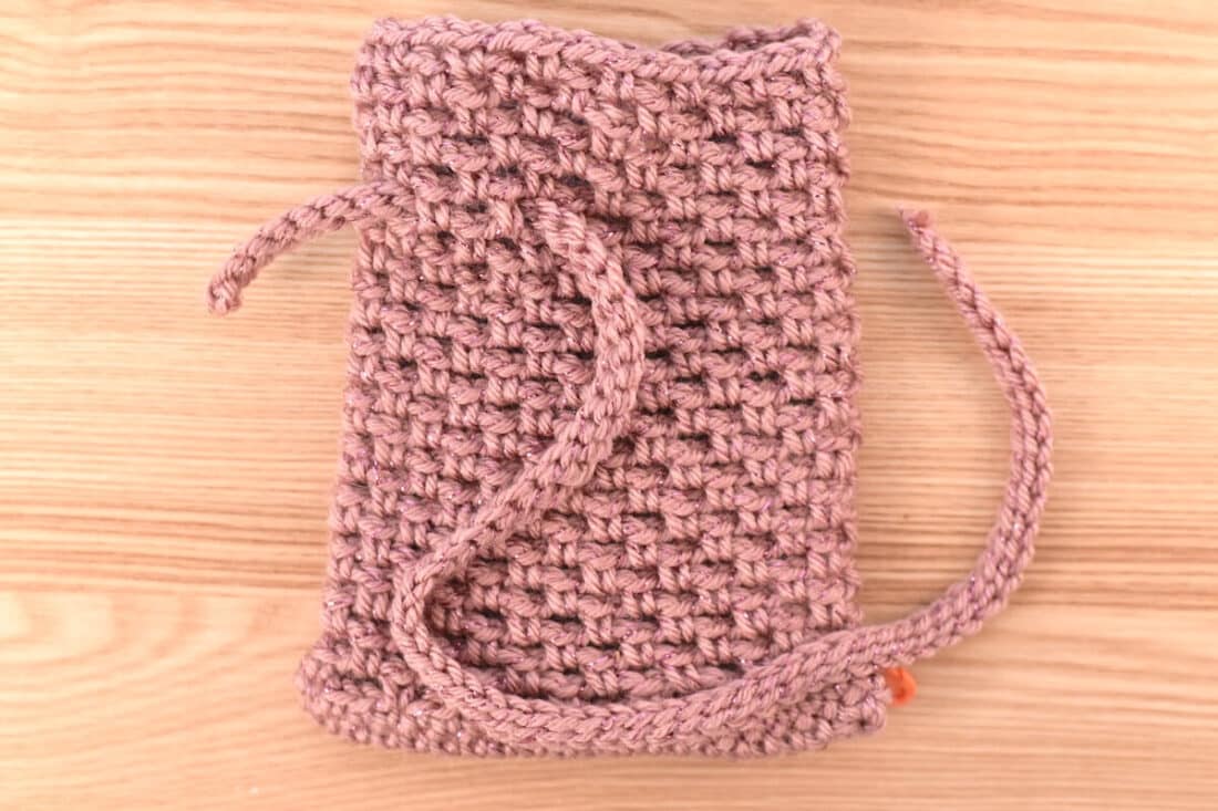 Close-up of the completed crochet bag after finishing the body of the bag, showing how to insert the string.