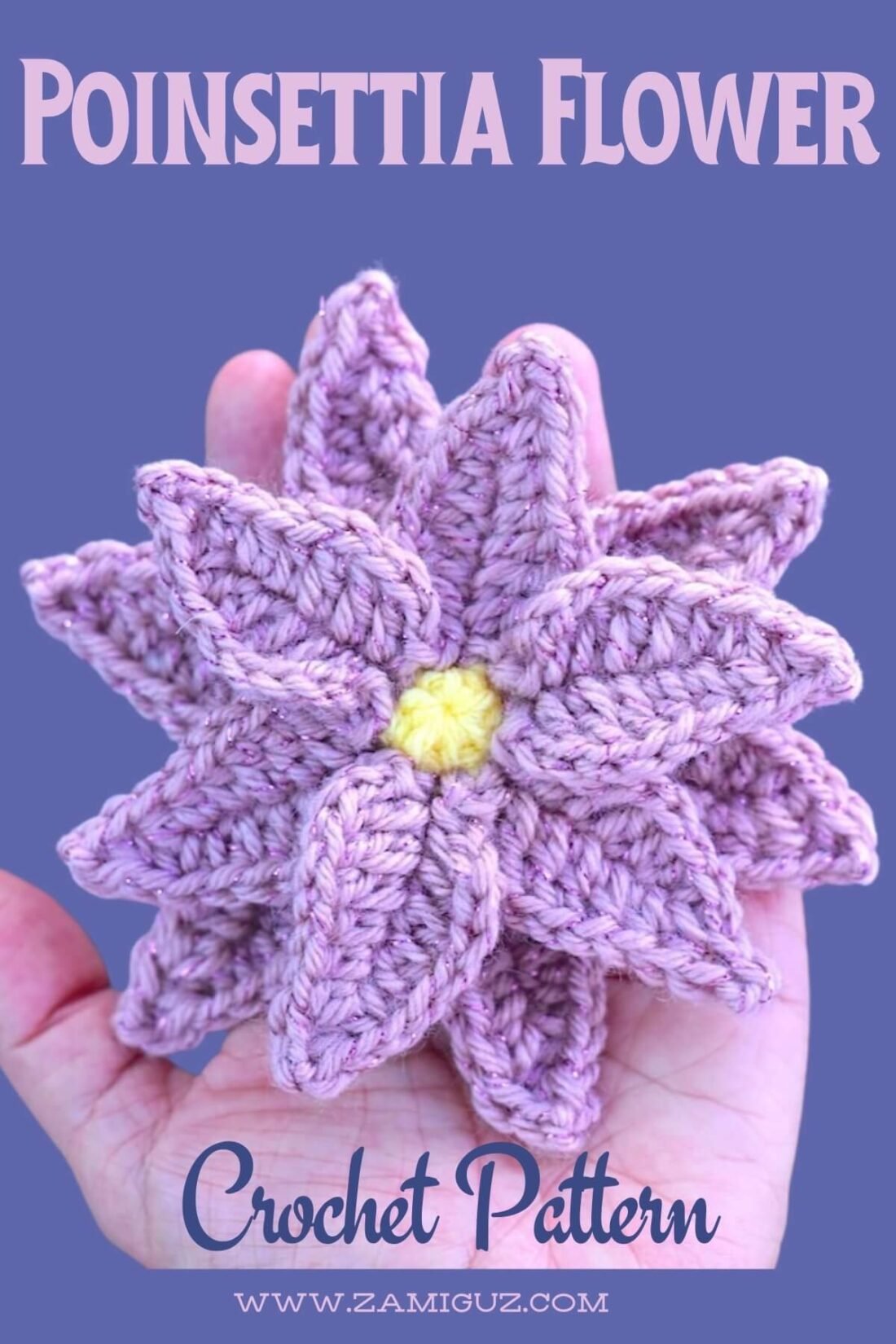 A crochet poinsettia flower with layered pink petals and a yellow center layered flat on a palm of a hand.