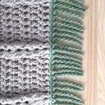 A close-up of a brown crochet swatch with a twisted fringe made with green yarn for crochet blankets.