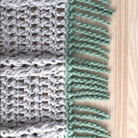 A close-up of a brown crochet swatch with a twisted fringe made with green yarn for crochet blankets.