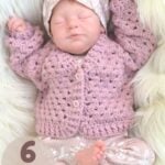 A life-like, asleep reborn baby doll dressed in a pink crochet baby cardigan.