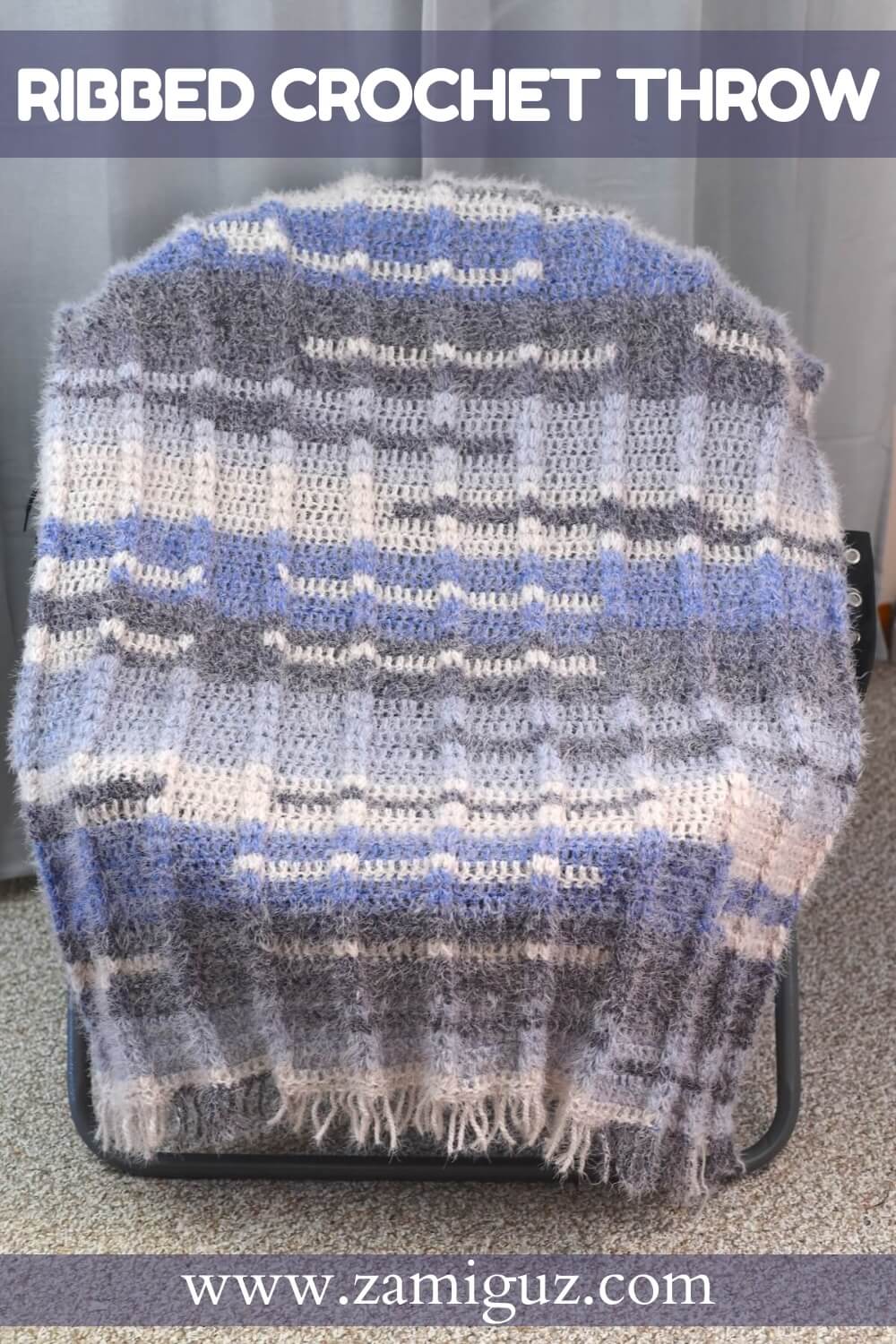 Crochet blanket draped over a chair, featuring ribbed texture and color blocks of gray, blue, and white.