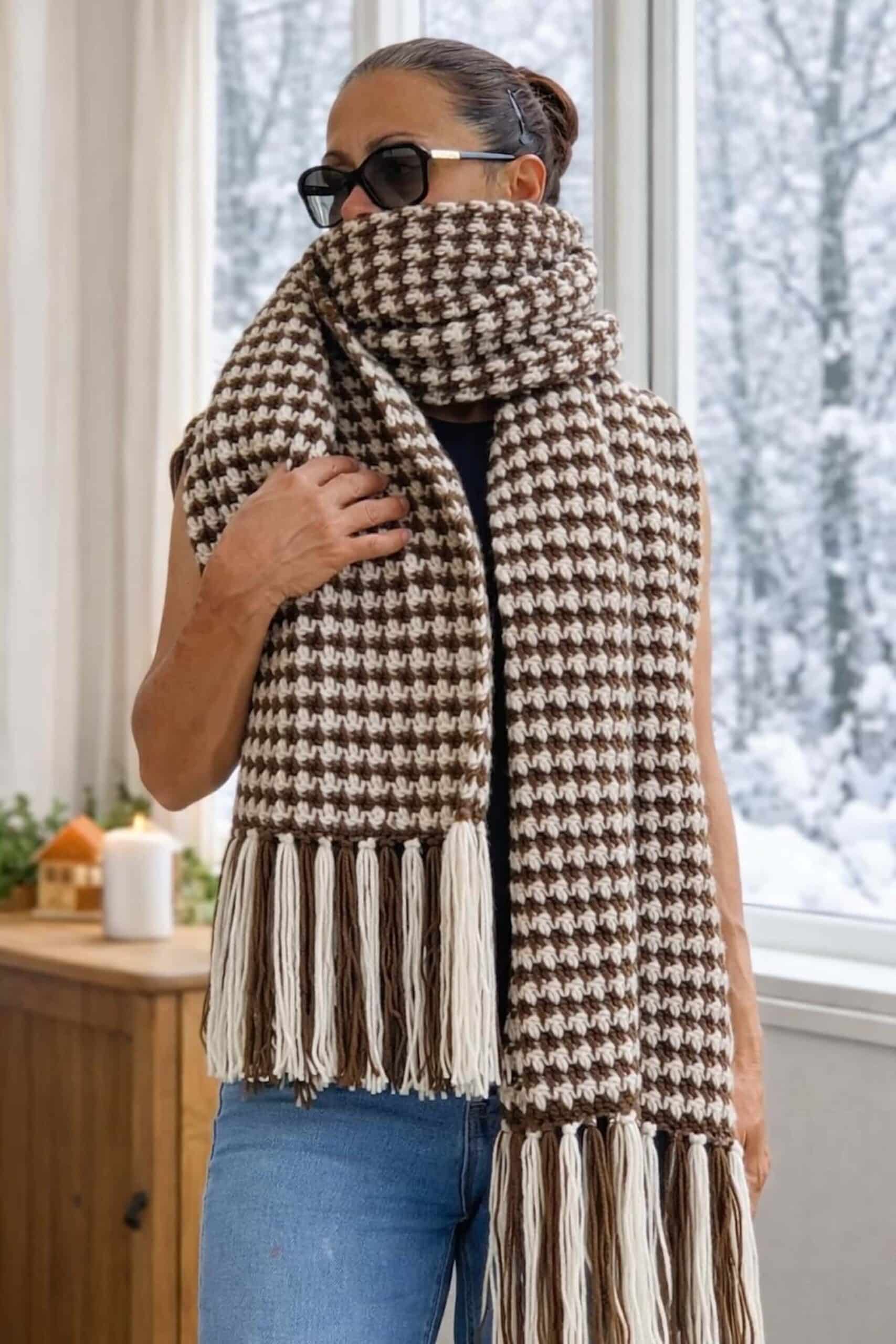 A woman wearing a brown and white, large crochet carf, with a checkered texture.