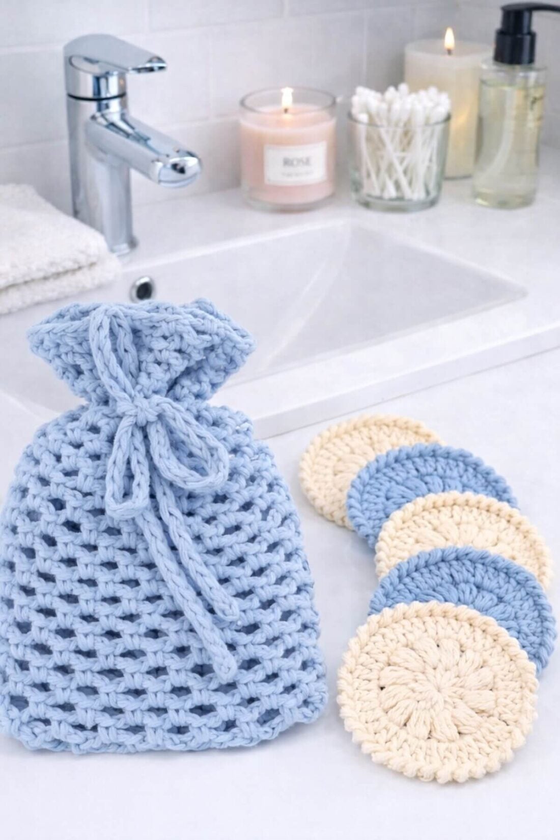 Crochet face scrubbies and matching drawstring bag made with cotton yarn, arranged as a reusable skincare set on a bathroom sink.