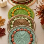 A crochet pumpkin placemat set in two sizes is decorating a Thanksgiving dining table.
