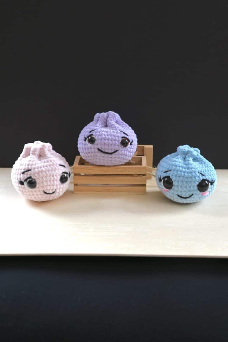 Blue, pink, and purple crochet dumplings with sweet embroidered facial details.